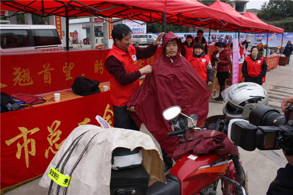 梧州市總工會(huì)的黨員義工們?cè)谑袞|出口春運(yùn)服務(wù)站助力“摩托大軍”平安返鄉(xiāng)，幫助他們檢查車輛和行李，穿上雨衣。--黃賀峰攝.j